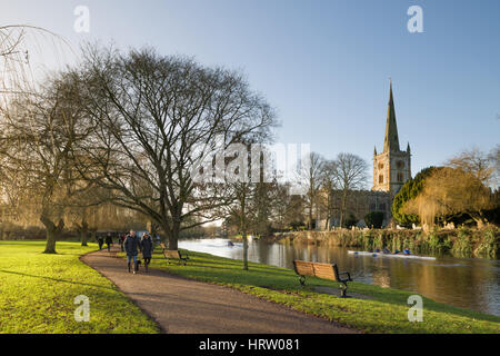 Le coppie a piedi e i canottieri sul fiume Avon nella parte anteriore della Chiesa della Santa Trinità, Stratford-upon-Avon, Warwickshire, Inghilterra, Regno Unito Foto Stock