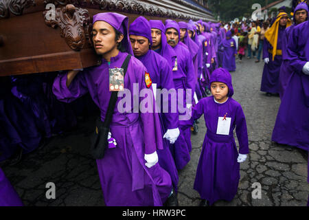 Antigua Guatemala - 16 Aprile 2014: un uomo che indossa vesti di porpora, portante un galleggiante (EUN) durante le feste pasquali, nella Settimana Santa, in Antigua Foto Stock