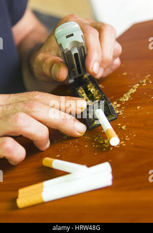 Uomo di rotolamento utilizzando le sigarette di tabacco fresco Foto Stock