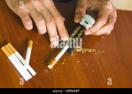 Uomo di rotolamento utilizzando le sigarette di tabacco fresco Foto Stock