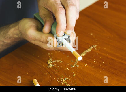 Uomo di rotolamento utilizzando le sigarette di tabacco fresco Foto Stock