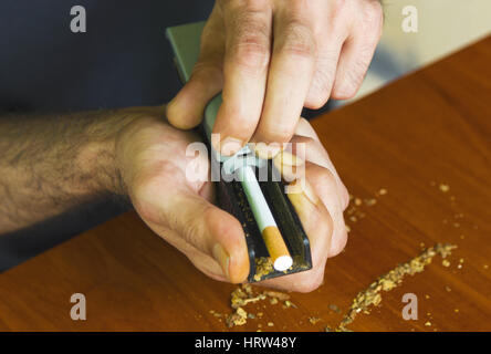 Uomo di rotolamento utilizzando le sigarette di tabacco fresco Foto Stock