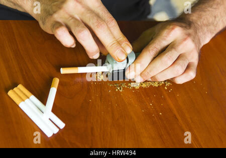 Uomo di rotolamento utilizzando le sigarette di tabacco fresco Foto Stock