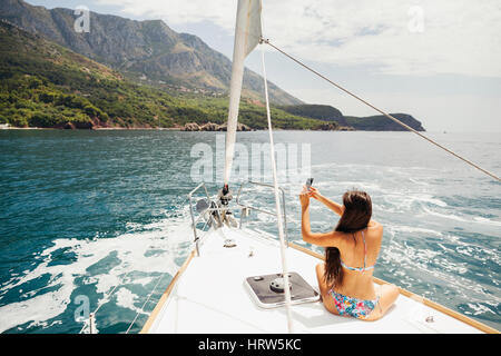 Ragazza yachting con lo smartphone Fotografia Viaggi in Crociera con la pittoresca vista mare in Montenegro Foto Stock