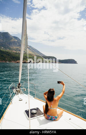 Ragazza yachting con lo smartphone Fotografia Viaggi in Crociera con la pittoresca vista mare in Montenegro Foto Stock