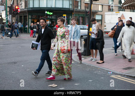 LONDON, Regno Unito - 22 Aprile 2016: coppia felice attraversando la strada nella zona di Brick Lane. Una ragazza in un lungo abito fiorito. L'uomo indossa occhiali. Foto Stock