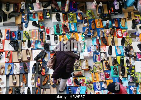 Barcellona, Spagna - 02 Marzo 2016: Donna navigando la grande varietà di scarpe in offerta a un mercato delle pulci di stallo a Mercat dels Encants a Barcellona. Foto Stock