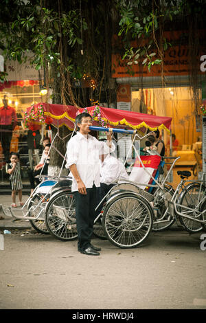 Hanoi, Vietnam - Aprile 25, 2014: nozze vietnamita rickshaw fumatori tradizionale vietnamita tubazione di tabacco. Foto Stock