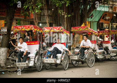 Hanoi, Vietnam - Aprile 25, 2014: nozze vietnamita rickshaws poggiante su decorate in rosso i veicoli di nozze in attesa per i clienti sulla strada. Foto Stock