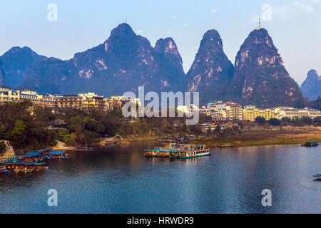 Vista del resort Città di Guilin in Cina centrale con molti edifici bianchi in barca sul fiume Peer e montagne carsiche sullo sfondo Foto Stock