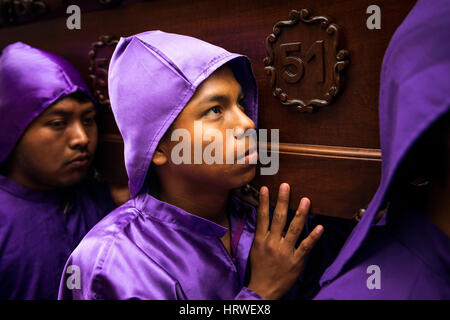 Antigua Guatemala - 16 Aprile 2014: un uomo che indossa vesti di porpora, portante un galleggiante (EUN) durante le feste pasquali, nella Settimana Santa, in Antigua Foto Stock