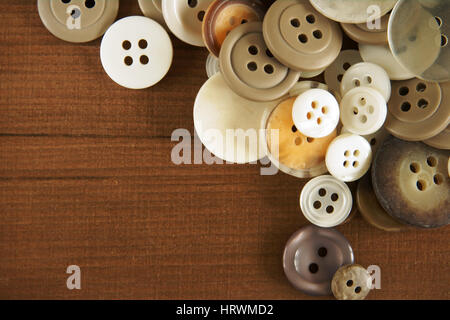 Pila di vecchio stile di colore marrone e beige pulsanti bianchi su uno sfondo di legno Foto Stock