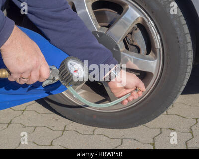 Un uomo è la misurazione della pressione di gonfiaggio di un pneumatico di una automobile Foto Stock