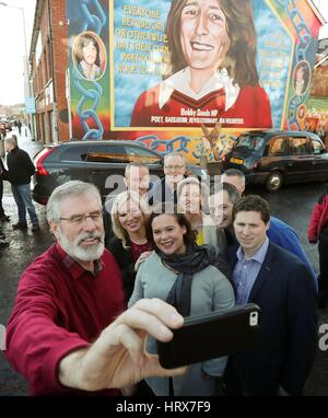 Sinn Fein Michelle O'Neill (centro sinistra), Mary Lou McDonald (centro destra) e Gerry Adams (sinistra) posa per una selfie nella parte anteriore del Bobby Sands murale dopo post elezione conferenza stampa al Sinn Fein sede a Belfast. Foto Stock