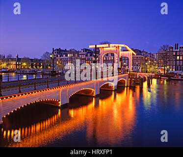 Skinny (ponte Magere Brug) riflettendo nel fiume Amstel di notte, Amsterdam, Olanda, Paesi Bassi Foto Stock