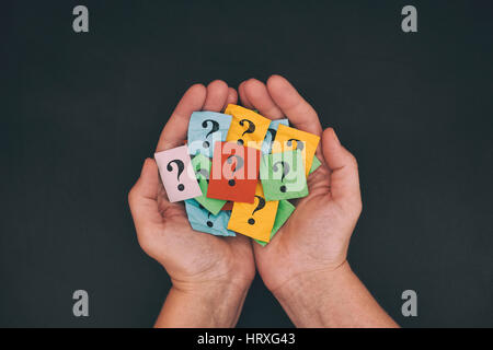 Troppe domande. Pila di carta colorata note con punti interrogativi nella mani. Primo piano. Foto Stock