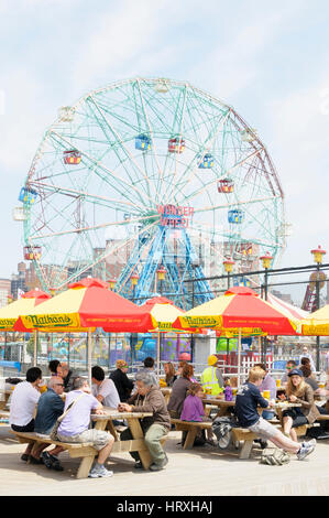 Persone mangiare nella parte anteriore della ruota di meraviglia, Deno il parco di divertimenti, Coney Island, Brooklyn, New York, Stati Uniti d'America Foto Stock