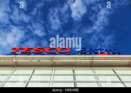 Tesco segno Extra in rosso e blu contro chiazzato bianco e blu cielo Foto Stock