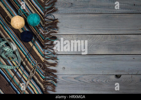 Frammento di manufatti in tessuto a maglia, aghi da maglia e palline di filato sul dipinto di bianco boards Foto Stock