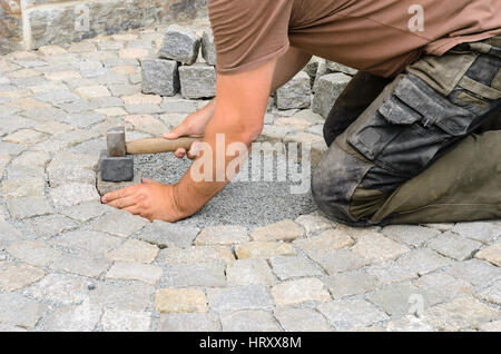 Operaio edile l'installazione di blocchi di pietra sul marciapiede Foto Stock