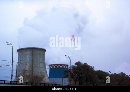 Impianto di produzione di tubi di fumo grigio in cielo molto nuvoloso Foto Stock