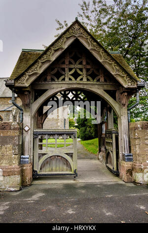 Bella elaborare scolpita in pietra e legno lychgate, ingresso al villaggio inglese chiesa Foto Stock