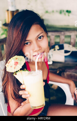 Attraente giovane ragazza asiatica in estate bere succo pineaple Foto Stock