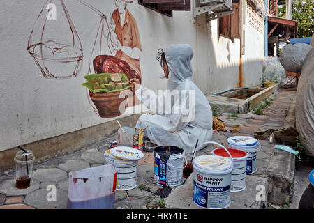 Thailandia Street art artista di strada muro art. Persone pittura muro. Donna che indossa indumenti protettivi. Sud-est asiatico Foto Stock