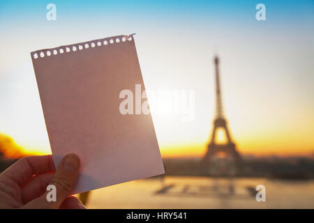 Mano azienda bianco carta vuoto vicino alla torre eiffel, messaggio da Parigi con il luogo per il testo Foto Stock