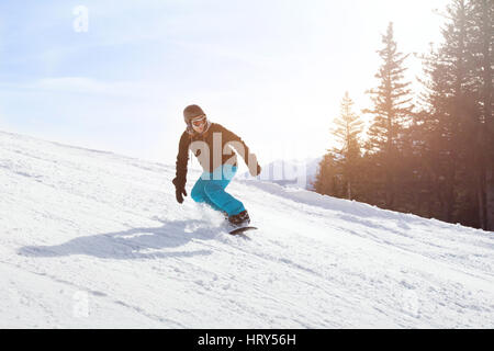Snowboard attività invernali, snowboarder in discesa su un pendio in montagna Foto Stock