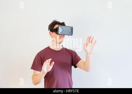 Uomo con occhiali per realtà virtuale su sfondo bianco Foto Stock