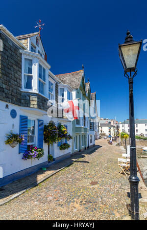 La bandiera inglese di St George essendo attraversato da una casa in Bayards Cove in Dartmouth, Devon, Inghilterra, Regno Unito Foto Stock