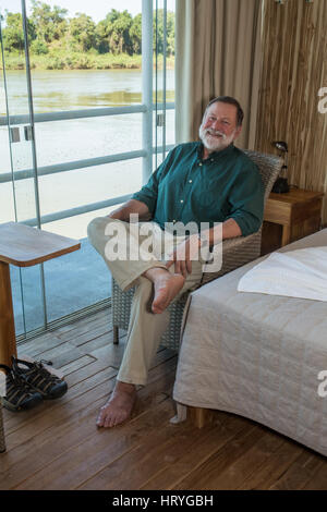 L uomo nella sua fine anni sessanta rilassante nella sua stanza in un albergo galleggiante (flotel), dopo una mattina su safari cercando giaguari, nella regione di Pantanal, Mato Foto Stock