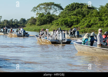 Un gruppo di imbarcazioni pieno di turisti in attesa di una Jaguar sulla riva di alzarsi dal suo riposo e di essere attivo nella regione di Pantanal, Mato Grosso, Sud Amer Foto Stock