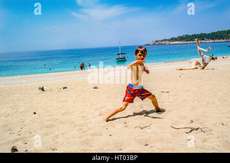 Little Boy esecuzione di arte marziale al mare spiaggia di sabbia dorata Foto Stock