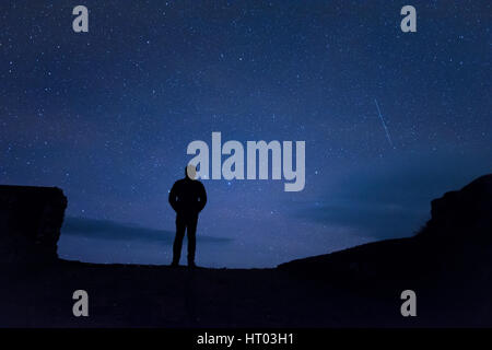 Uomo in piedi sotto le stelle di notte - cornwall, Regno Unito Foto Stock