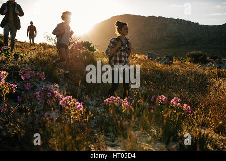 Gruppo di amici sono le escursioni in montagna in una giornata di sole. Quattro giovani passeggiate attraverso la campagna. Foto Stock