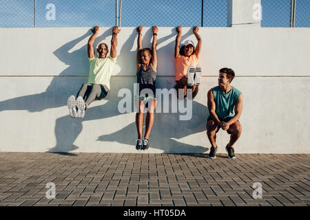 Gruppo di persone aventi una divertente durante la sessione di allenamento all'aperto. Amici appesa a una parete e stretching dopo la sessione in esecuzione. Foto Stock