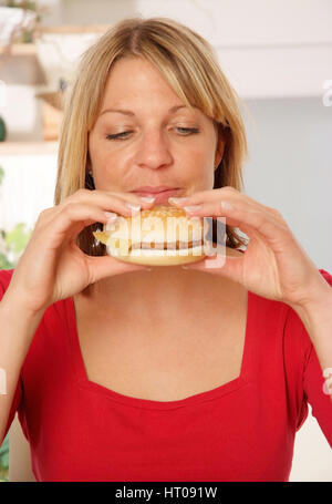 Junge Frau beisst in einen Burger - donna mangia Burger Foto Stock
