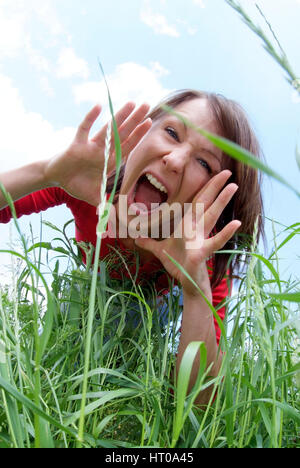 Schreiende Frau im Gras - urlando donna in erba Foto Stock