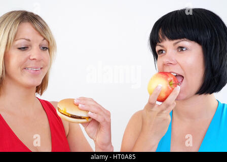 Frauen Burger Essen und Apfel - donne mangiare hamburger e Apple Foto Stock