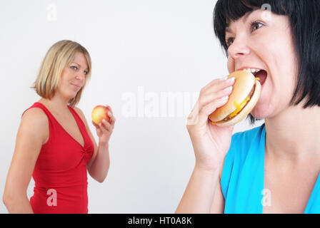 Frauen Burger Essen und Apfel - donne mangiare hamburger e Apple Foto Stock