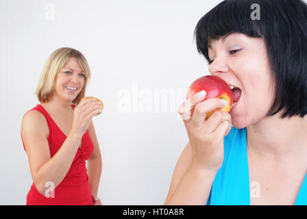 Frauen Burger Essen und Apfel - donne mangiare hamburger e Apple Foto Stock