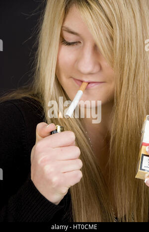 Jugendliches M‰dchen z'ndet sich eine Zigarette un - Teenager fuma una cigaret Foto Stock