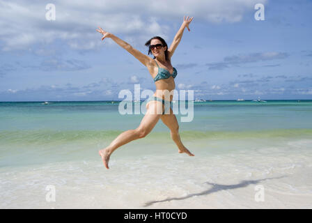 Junge, vitale Frau im springt Bikini am Strand - giovane donna salta sulla spiaggia Foto Stock