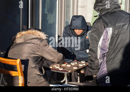 Pechino, Cina - Dic 2013 - tre uomini giocare l'antico gioco cinese del Xiangqi in un freddo angolo di strada in inverno a Pechino. Foto Stock