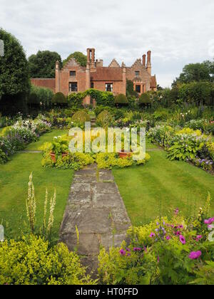 Sunken garden a Chenies Manor House nei primi giorni di luglio. Lussureggiante nuova crescita, Herbaceous borders, strisce di prato e featured stagno ornamentale con erbe. Foto Stock