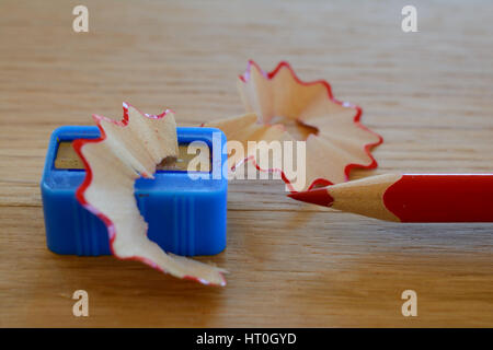 Colore rosso matita, sharpener e trucioli sul tavolo di legno. Profondità di campo. Foto Stock