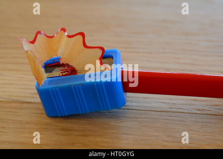 Colore rosso matita, sharpener e trucioli sul tavolo di legno. Profondità di campo. Foto Stock