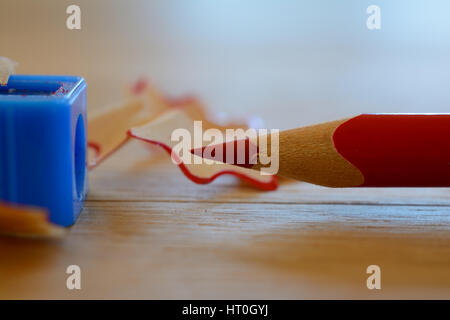 Colore rosso matita, sharpener e trucioli sul tavolo di legno. Profondità di campo. Foto Stock